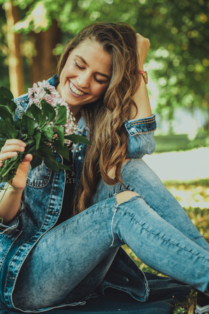 Beautiful happy young woman holding flowers in her hand. Close up portrait of a smiling girl.の写真素材