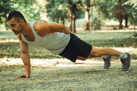 Portrait of a fitness man doing push ups in the park