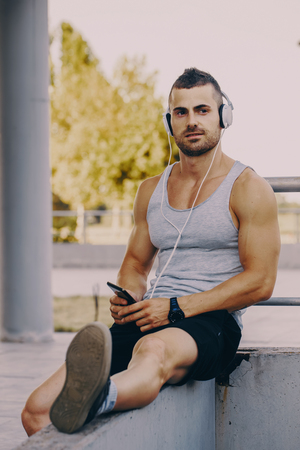 Tired exhausted athletic man in sportswear resting after running outdoors.の写真素材