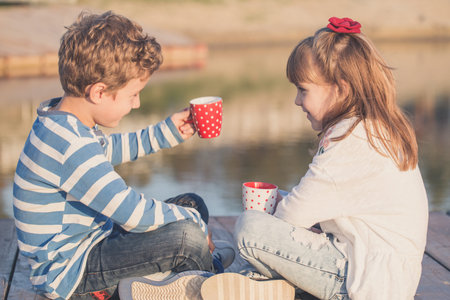 Girl and boy playing on the beach at sunset time. First love.Happy kids enjoying the lake while...