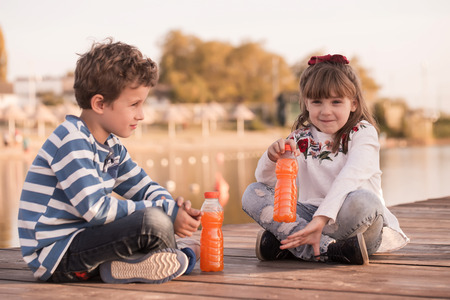 Girl and boy playing on the beach at sunset time. First love.Happy kids enjoying the lake while  having a good time.の写真素材