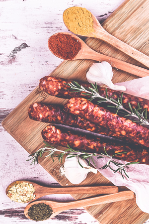 Smoked very delicious sausage with rosemary and spices in spoons on a wooden rustic background. Top view.の写真素材