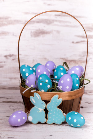 Easter gingerbread cookies and eggs in a basket on wooden table. Rabbits and eggs. Greeting card....