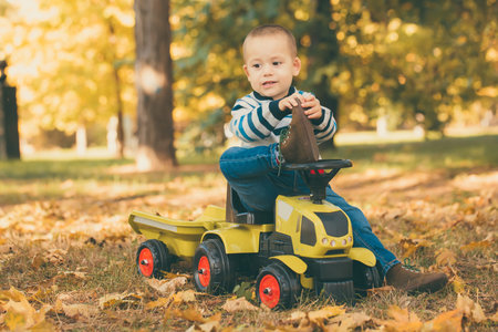 Little happy  boy toddler driving a toy truck in park outdoorsの写真素材