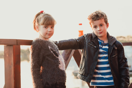 Girl and boy playing on the beach at sunset time. First love.Happy kids enjoying the lake while  having a good time.の写真素材