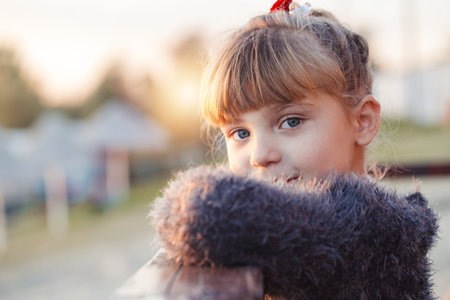 Close up portrait of a beautiful smiling little girl outdoors. She enjoys a beautiful sunny dayの写真素材