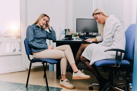 Doctor talking with female patient in doctors office.の写真素材