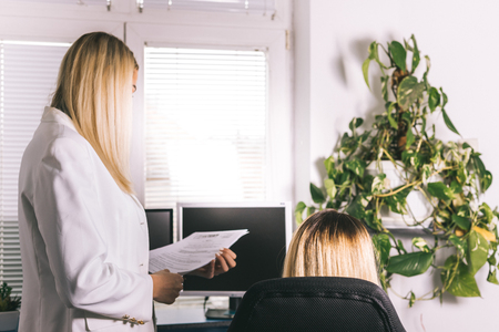 Two young female colleagues having meeting and discussing paperwork. Managers discuss new candidates searching for job , choose best resume to invite seeker at interviewの写真素材