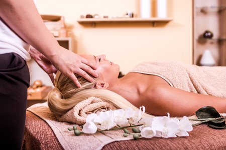 Beautiful young woman having face or head massage  in spa salonの写真素材