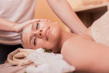 Young beautiful woman lying on massage table and enjoying massage.の写真素材
