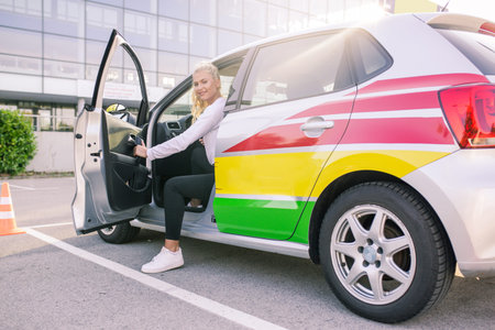 Driving school. Young happy woman or driving student getting out of the car. Free space for text. Copy space. Lens flareの写真素材
