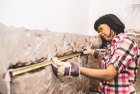 Clever woman repairing her bathroom sink pipe with  positive attitude. Using measuring tape ruler.の写真素材