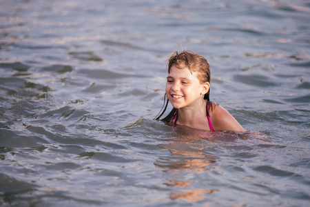 Happy little girl swimming in water on hot summer day.の写真素材