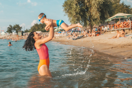 Three year old toddler boy playing with mother in the water. Happy mother holding little boy in her arms. Happy family. Vacation, travel conceptの写真素材