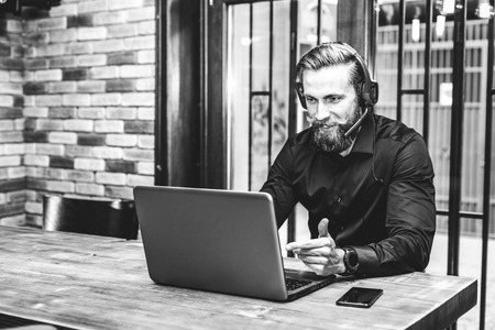 Bearded  businessman with laptop and headset talking during video conferenceの写真素材
