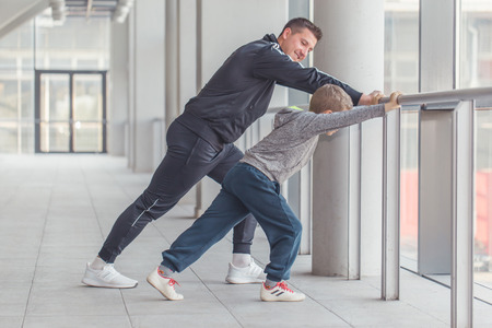 Little boy and his trainer exercising together at a sports center. Father and son spend time together and lead a healthy lifestyle.の写真素材