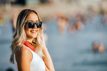 Portrait of happy young woman with sunglasses standing at the Beach. Smiling woman looking at camera. Happy, Emotion,People, Lifestyle Concept.の写真素材