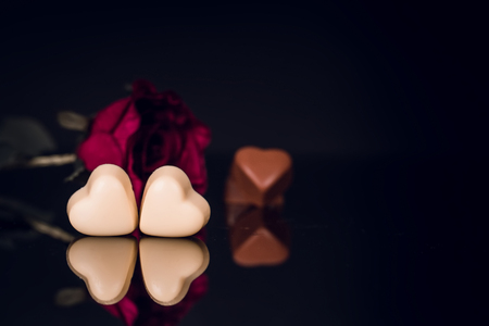 Valentines day greeting card with red rose and heart shaped chocolate on black backgroundの写真素材