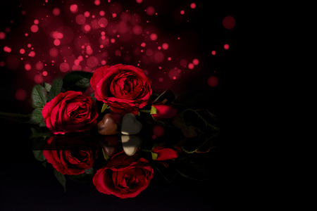 Valentines day greeting card with red roses and heart shaped chocolate with lights on black backgroundの写真素材