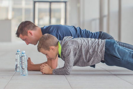 Little boy and his father exercising together at a sports center. Father and son spend time together and lead a healthy lifestyle.Working Out Together. Fitness Day. Sporty Family Concept. Active Lifestyleの写真素材