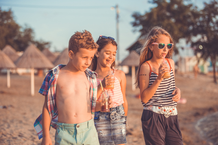 Portrait of happy children while having fun walking on the shoreの写真素材