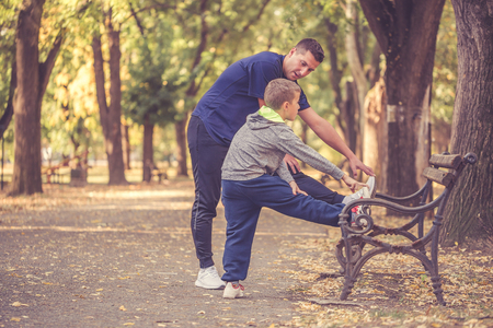 Little boy and his father exercising together in the park. Father and son spend time together and lead a healthy lifestyle.Working Out Together. Fitness Day. Sporty Family Concept. Active Lifestyleの写真素材