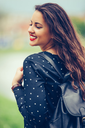 Portrait of a cheerful smiling girl with backpack  while walking outdoors.  - Imageの写真素材