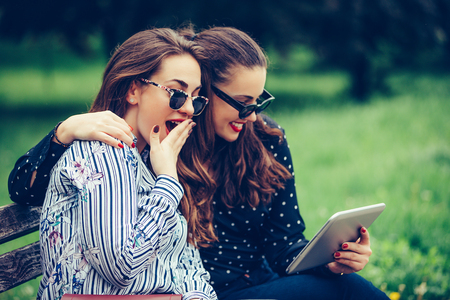 Two beautiful female friends using a digital tablet surprised with the good  news - Imageの写真素材