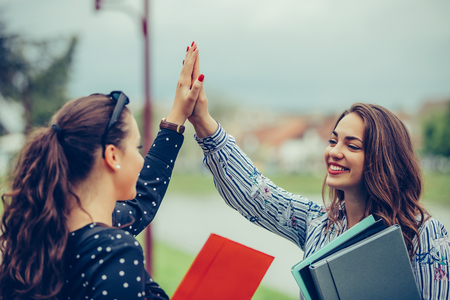 Two happy female students are giving high five after successfully learning - Imageの写真素材