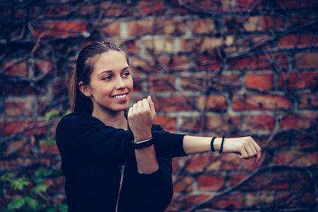 Young beautiful woman stretching her arms, brick wall in the background.の写真素材