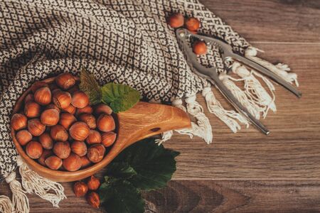 Hazelnuts with green leaves in wooden bowl on rustic brown background. Top viewの写真素材
