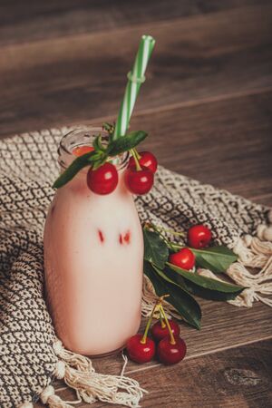 Cherry smoothie or milkshake in jar with fresh cherries on rustic wooden background, healthy food for breakfast and snackの写真素材