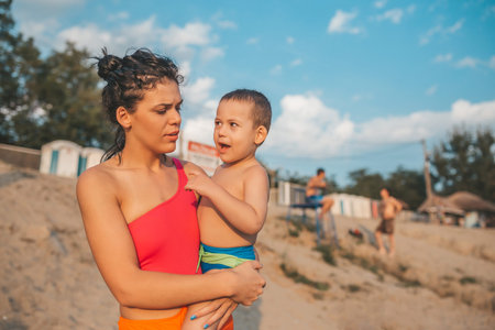 Happy mother with her son enjoy the beautiful sunny day on the beach. Mother holding little son in...