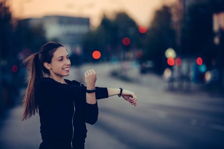 Young woman stretching her arms in the city, preparing for evening workoutの写真素材