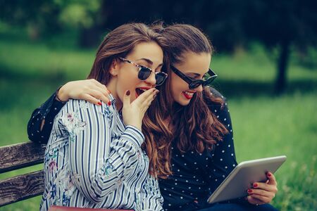 Two beautiful female friends using a digital tablet surprised with the good newsの写真素材