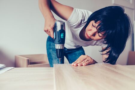 Woman assembling new furniture and using a cordless drill.の写真素材