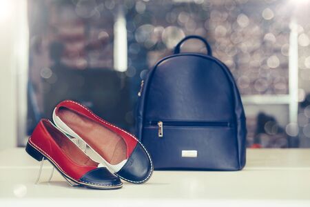 Pair of stylish women leather shoes with backpack in the background in a store.の写真素材