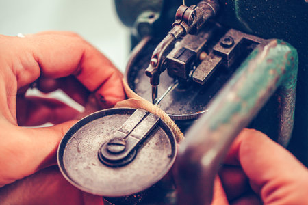 Close up of a female shoemaker hands stitching a part of the shoe at a workshopの写真素材