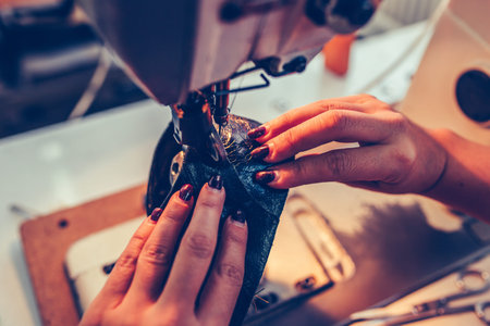 Close up a female shoemaker hands stitching a part of the shoe at a workshop