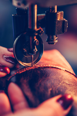 Hands of an experienced seamstress stitching a part of the shoe  in the handmade footwear industry