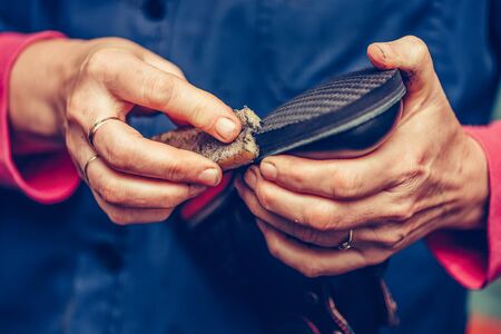 Hands of an experienced cobbler in the handmade footwear industry, finishing the soles of the shoes. Selective focus and small depth of field.の写真素材