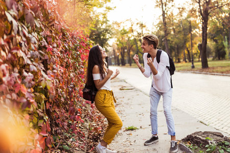Excited young couple or friends celebrating success raising arms, on the street