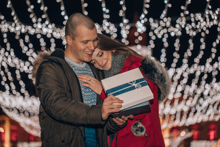 Young romantic couple is having fun outdoors in winter before Christmas. Romantic surprise for...