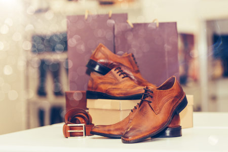 Close up of a elegant men's leather shoes of different models, belt and shopping bags in a background on the shelf at the shoe store. Copy space.の写真素材