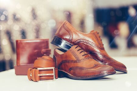 Pair of elegant men's leather shoes, wallet and belt on a shelf of a shop. Copy space.の写真素材