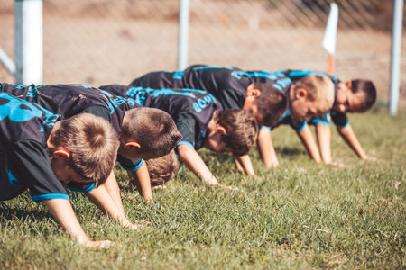  Group of young football players perform warm-up exercises before football training. Young players  doing push-up exercises outdoor.の写真素材