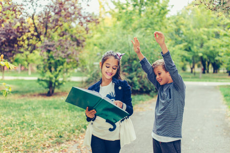 Happy little children celebrating success with raised hands. Two happy kids celebrating excellent results on a test at school.