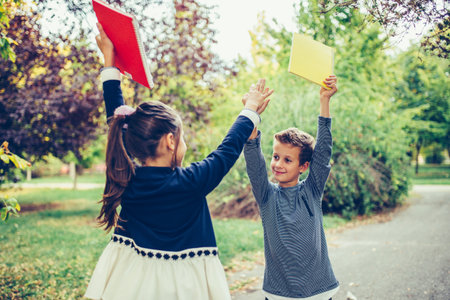 Happy little children celebrating success while giving high five . Two happy kids celebrating excellent results on a test at school.
