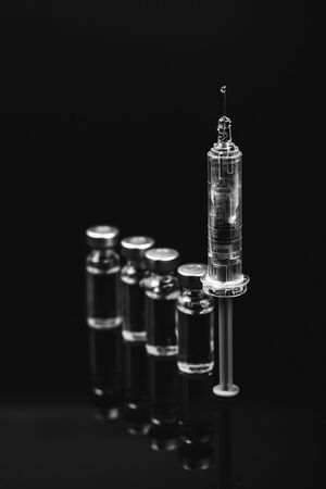 Medical vials for injection with a syringe and ampoules on black background. Blac and white photo.の写真素材
