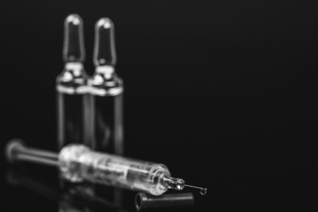 Medical vials for injection with a syringe and ampoules on black background. Black and white photo.の写真素材